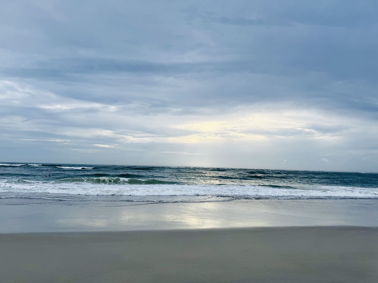 Waves along St. Augustine Beach beneath a soft blue sky